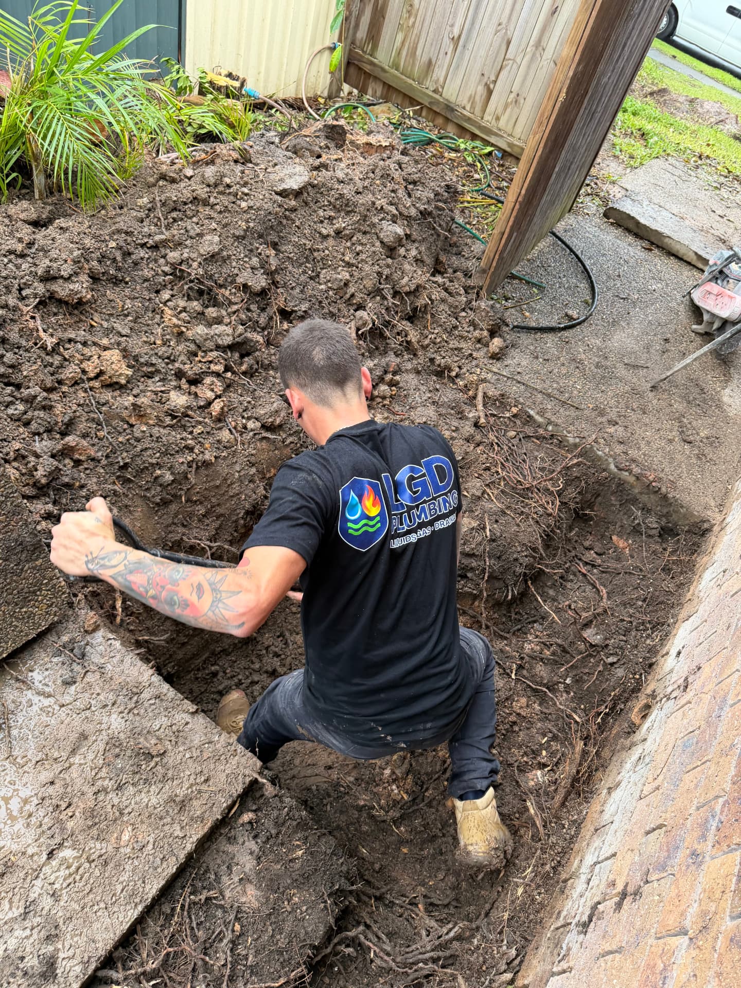 Luke from LGD Plumbing working on drainage in a backyard trench